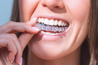 woman smiling while putting on clear aligner