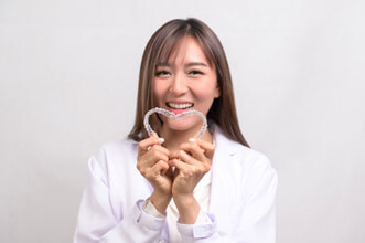 woman smiling while creating heart-shaped with clear aligners