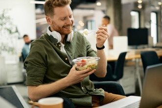man smiling while eating lunch at office