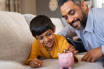 Father watching son put coin in piggy bank