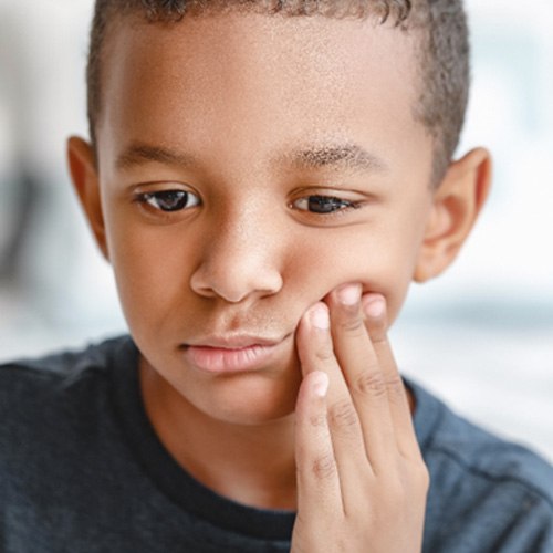 Sad young boy with tooth in pain; child dental emergency in Levittown, PA