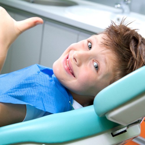 Young boy in dental chair giving a thumbs up