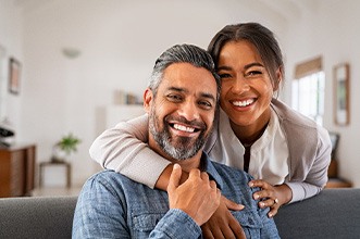 Smiling couple hugging on couch in living room