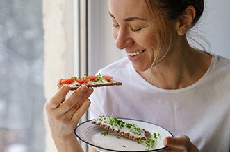 Woman smiling while eating healthy snack at home