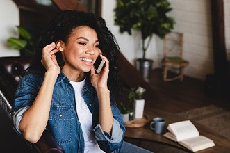 Woman smiling while talking on cell phone at home