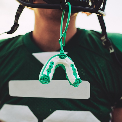 Green sportsguard hanging from football helmet
