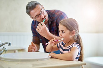 Dad and daughter brushing teeth in bathroom