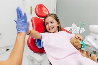 Child smiling while giving dentist high-five