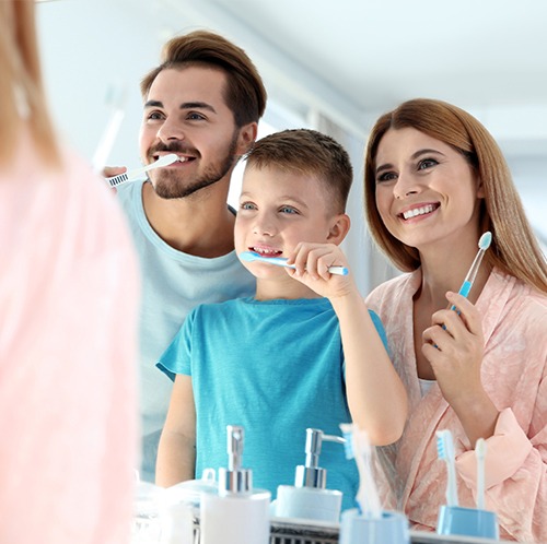 Mother father and son brushing teeth together