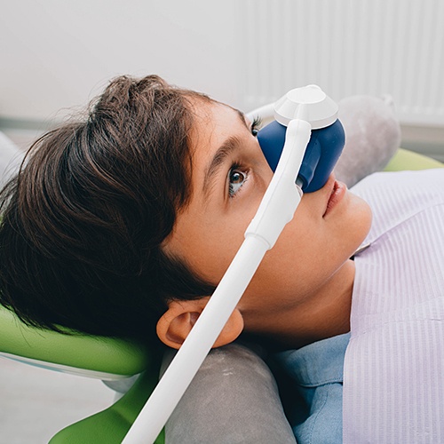 Child with nitrous oxide sedation dentistry mask in place during dental visit