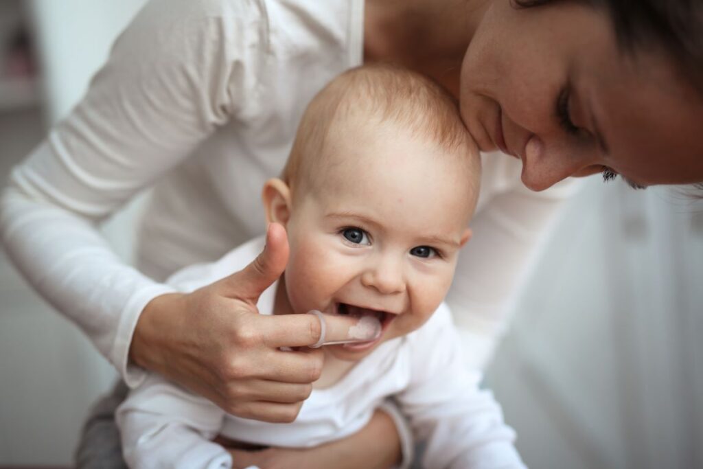 A mother brushing a baby’s gums